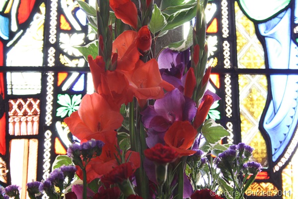 COLOUR COORDINATING_Flowers in front of a stained-glass window.