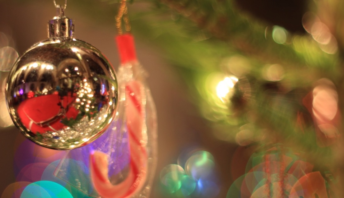 A bauble hangs from a Christmas tree. In it, the interior of St Luke's is visible.