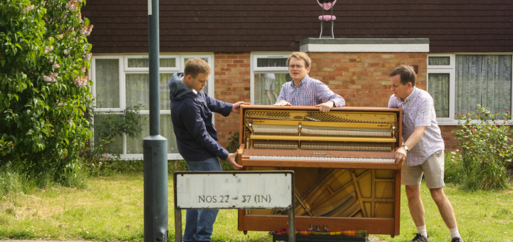 Andrew, Matthew, and Richard Burdett moving the donated piano up the road.