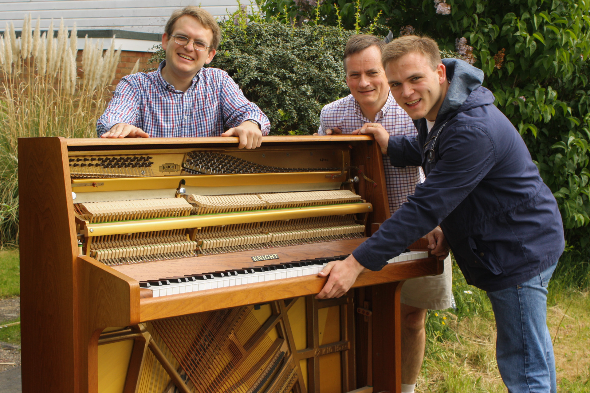 Matthew, Richard, and Andrew Burdett smile for the camera, during the piano move.